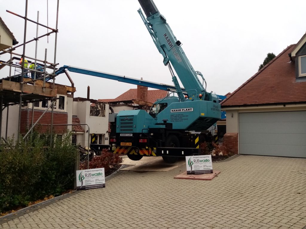 RJS Waste Management Chichester signs up in front of a crane at a building demolition site in Hampshire 