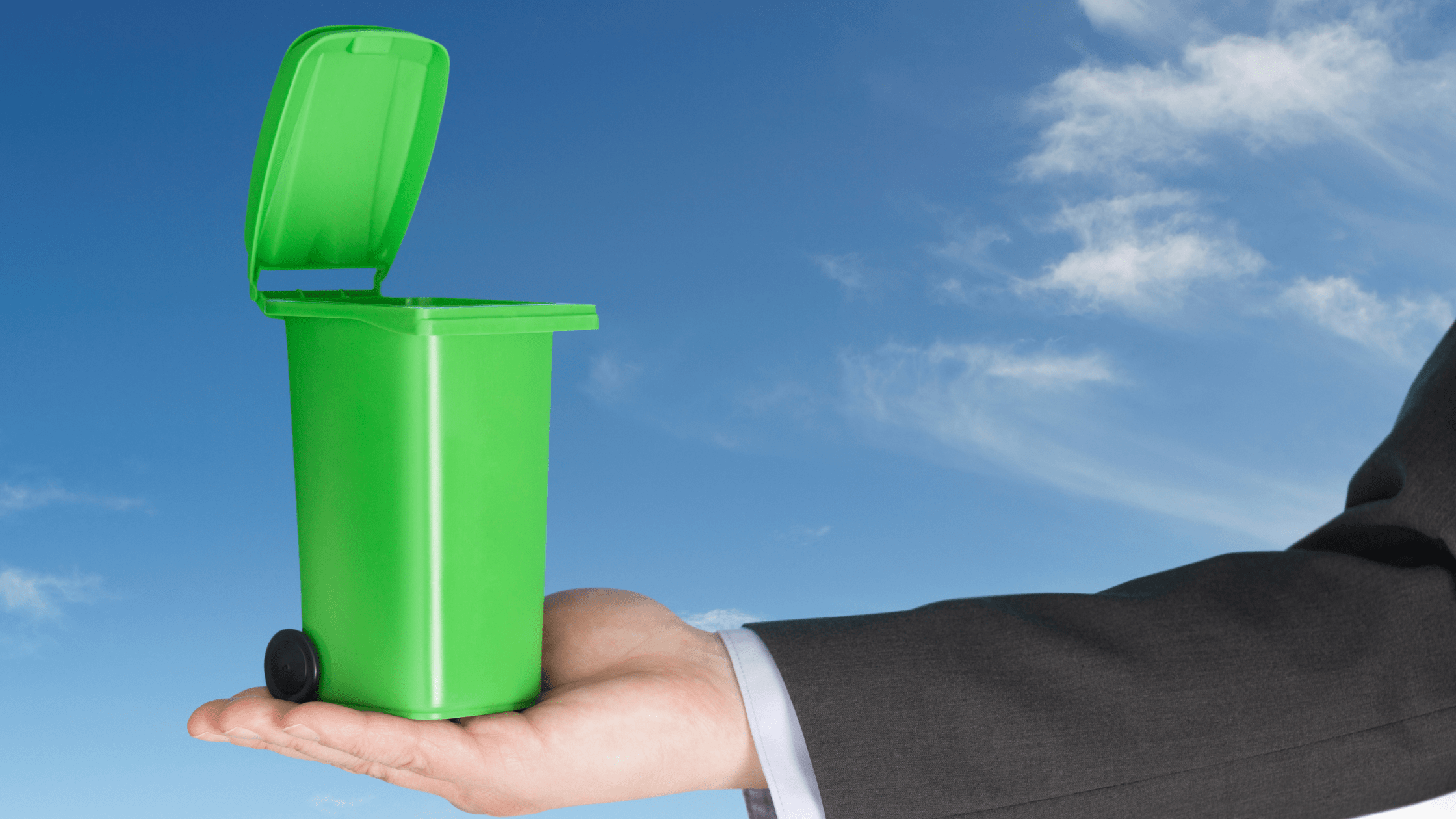 Business man in a suit holding a green bin to represeant sustainable waste management