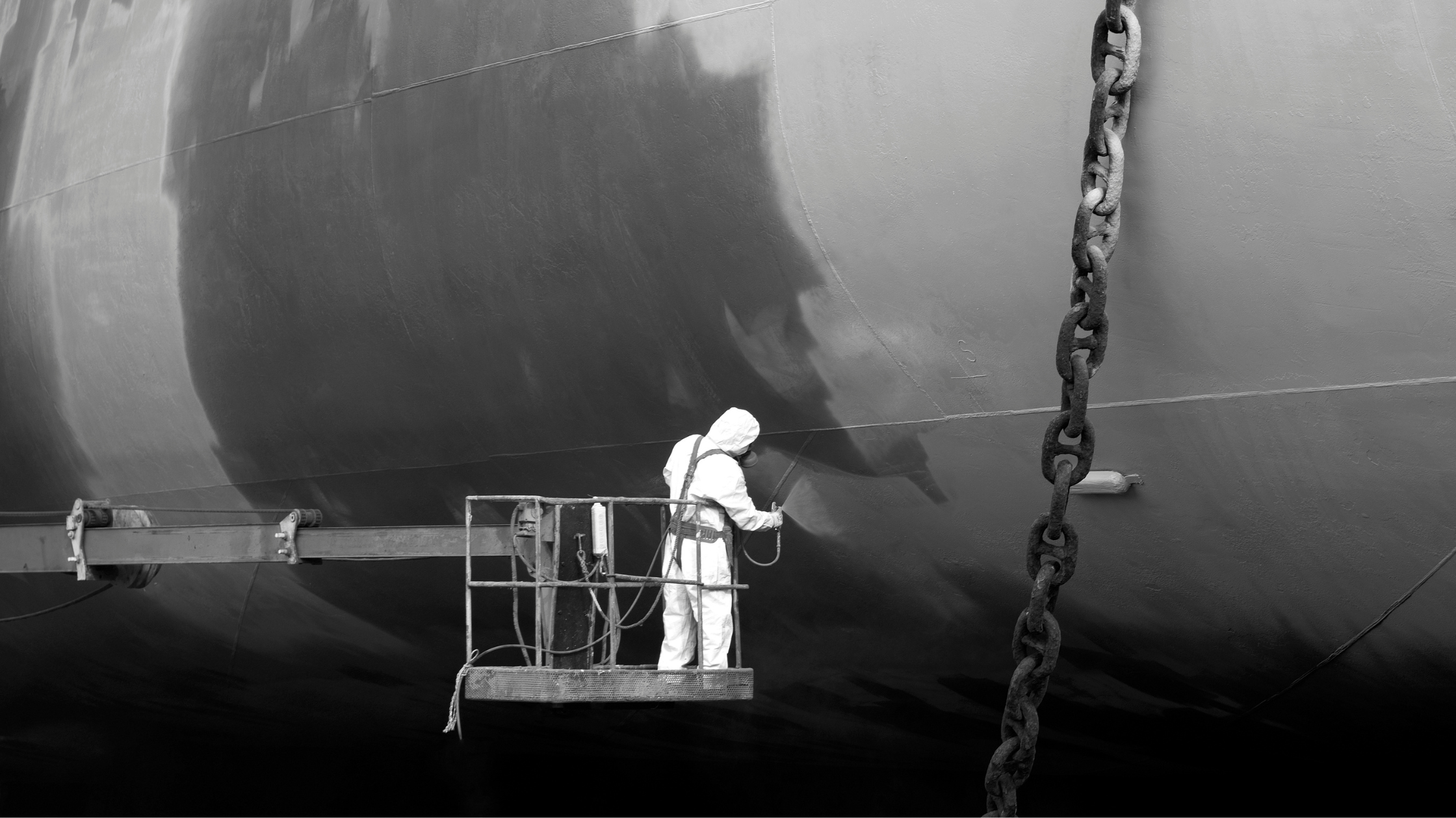 Man in protective clothing cleans ship. Paint used on ships could cause exposure to asbestos in shipyards