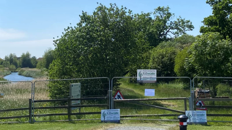 site clearance and excavation banner RJS Waste Management sign on a lakeside area fenced off for site clearing and excavation on a West Sussex housing estate