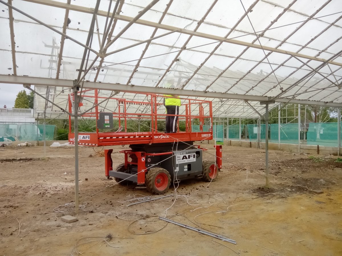 RJS Waste demolition contractor standing Mobile Elevated Work Platform to remove glass panels from greenhouse